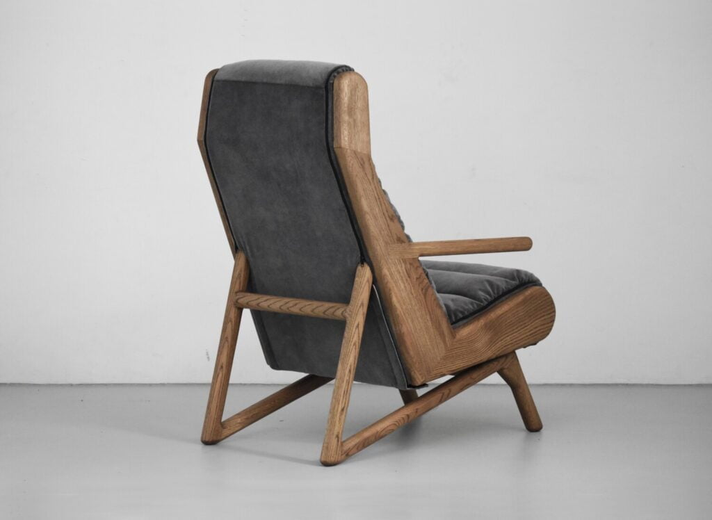 dębowy fotel Cameleon z pikowaną odsuwaną tapicerką w minimalistycznym wnętrzu z lampą Flos